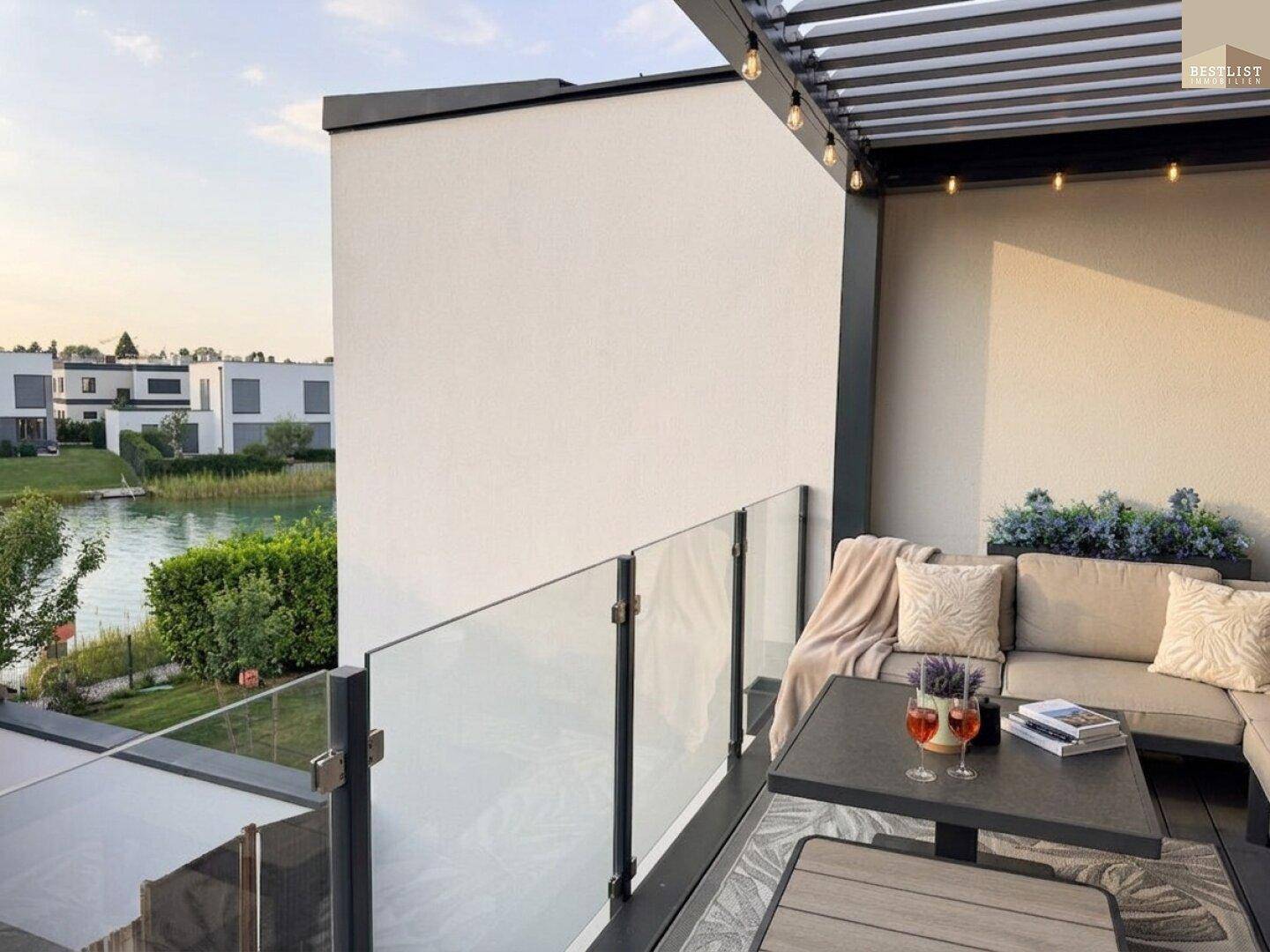 Gemütlicher Balkon mit Sitzgelegenheiten, Blick auf den See und moderne Überdachung.