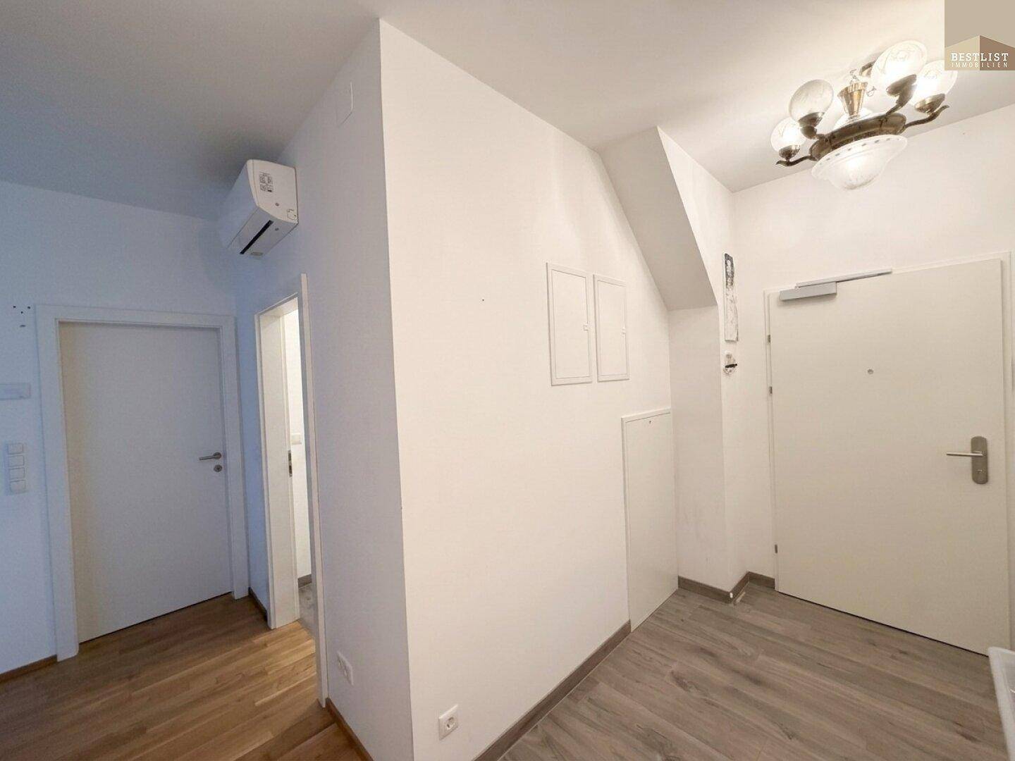 Heller Eingangsbereich mit Holzboden, Klimaanlage und Zugang zu weiteren Räumen.