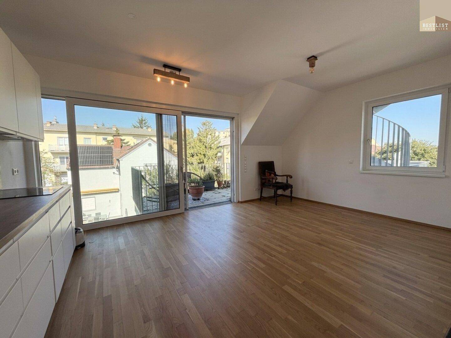 Heller Wohnbereich mit Holzboden, großen Schiebetüren zum Balkon und Blick ins Grüne.