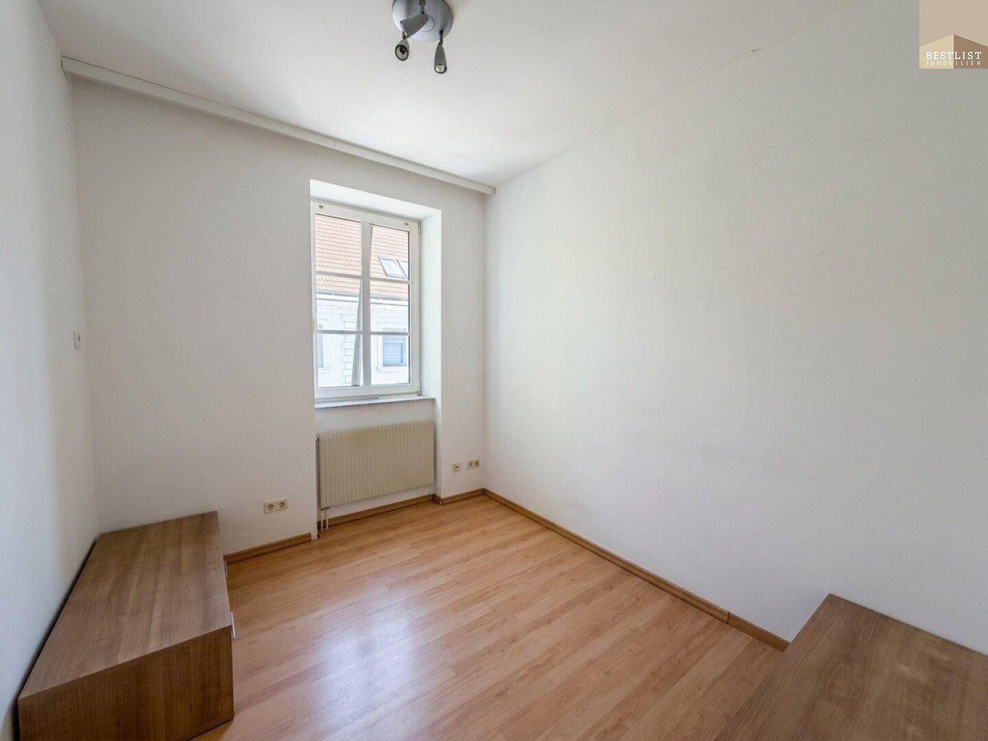 Gemütliches Zimmer mit Holzboden, weiß gestrichenen Wänden und einem Fenster mit Fernblick.
