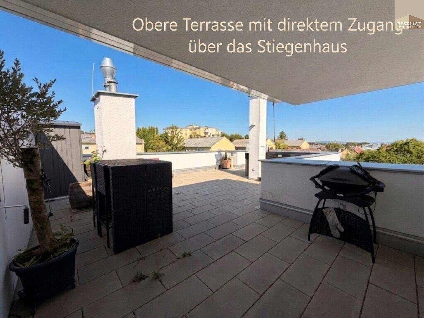 Geräumige Dachterrasse mit Fliesenboden, Sitzgelegenheiten und Grillbereich unter blauem Himmel.