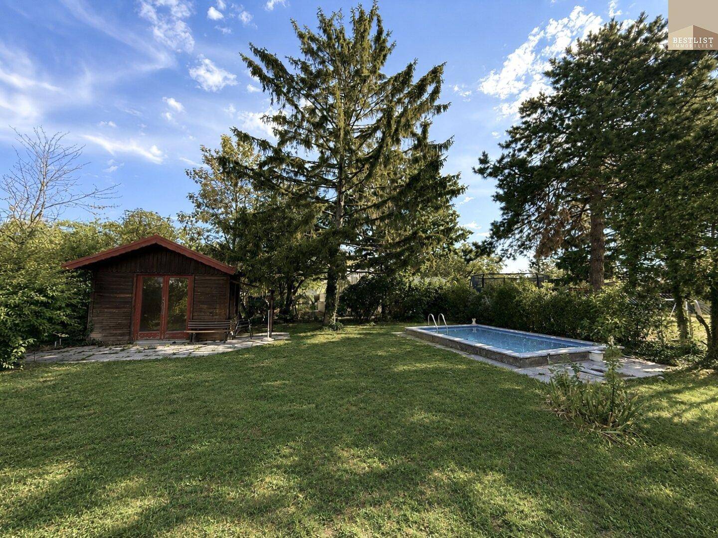 Weitläufiger Garten mit privatem Pool und Gartenhaus unter hohen Bäumen.