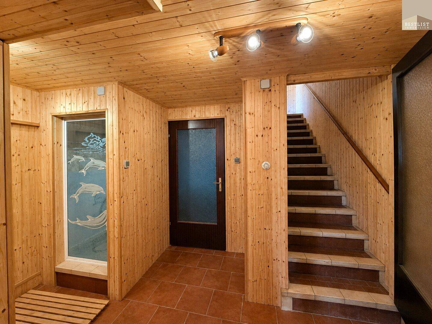 Rustikaler Flur im Untergeschoss mit Holzverkleidung und Zugang zur Treppe.