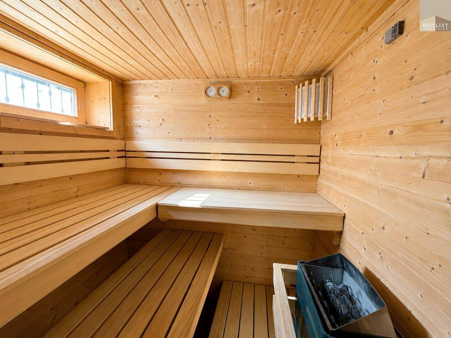 Geräumige Holzsauna mit Bänken und Heizofen, perfekt zur Entspannung.