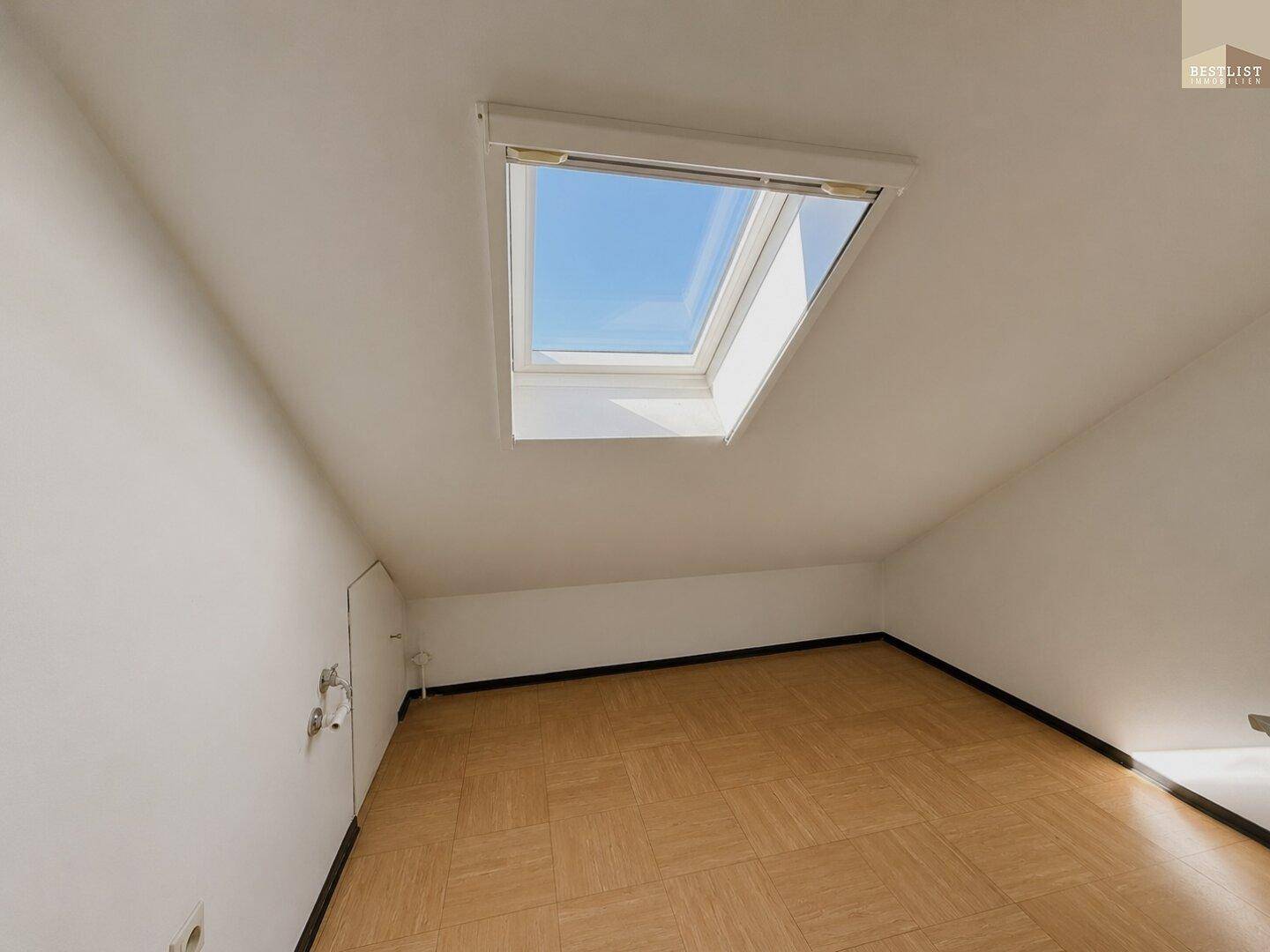 Dachbodenraum mit Holzparkett und großem Dachfenster für viel Licht.
