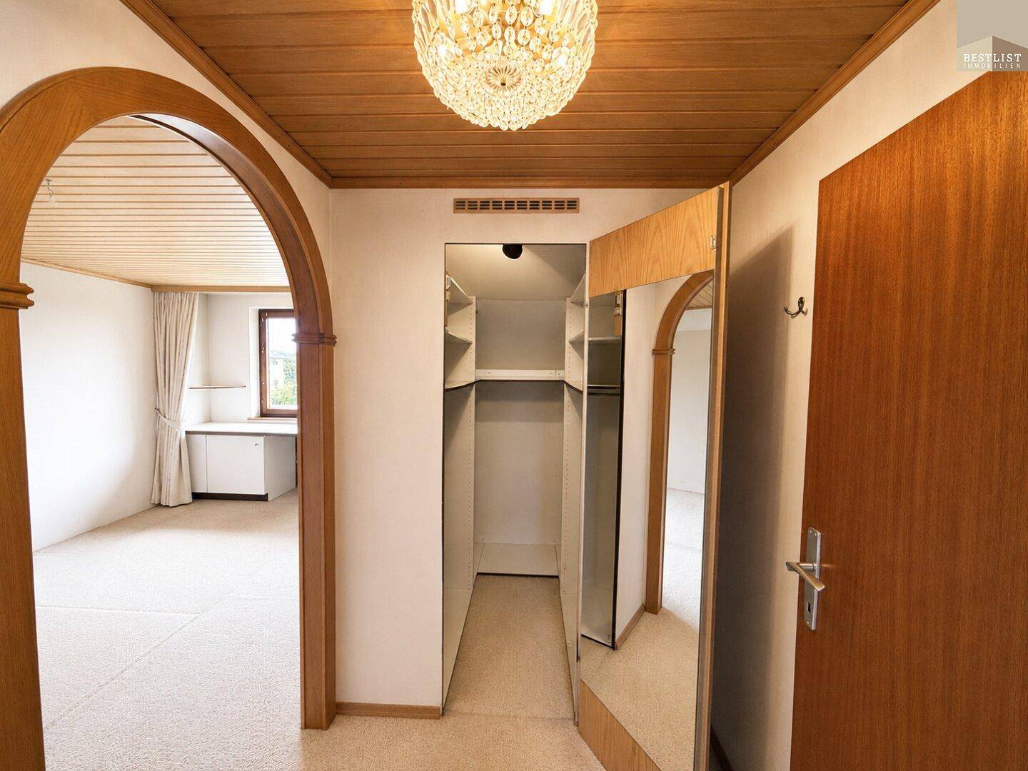 Flur mit Einbauschrank und Spiegel, der zu einem weiteren Zimmer führt.
