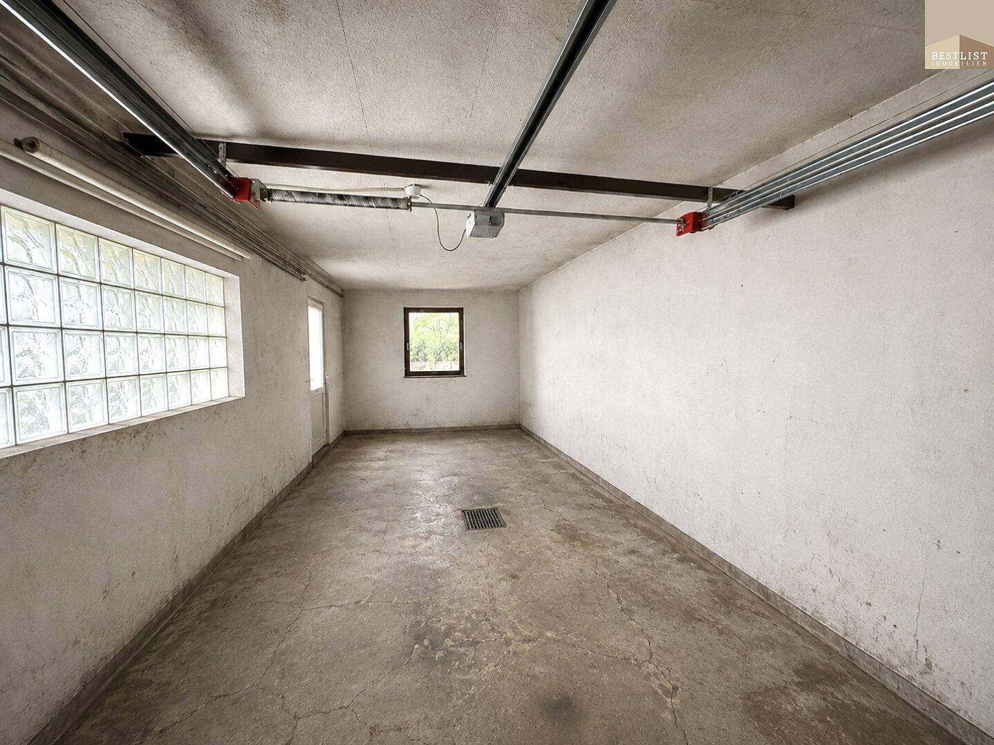 Geräumige Garage mit Betonboden und Fenstern für Tageslicht.