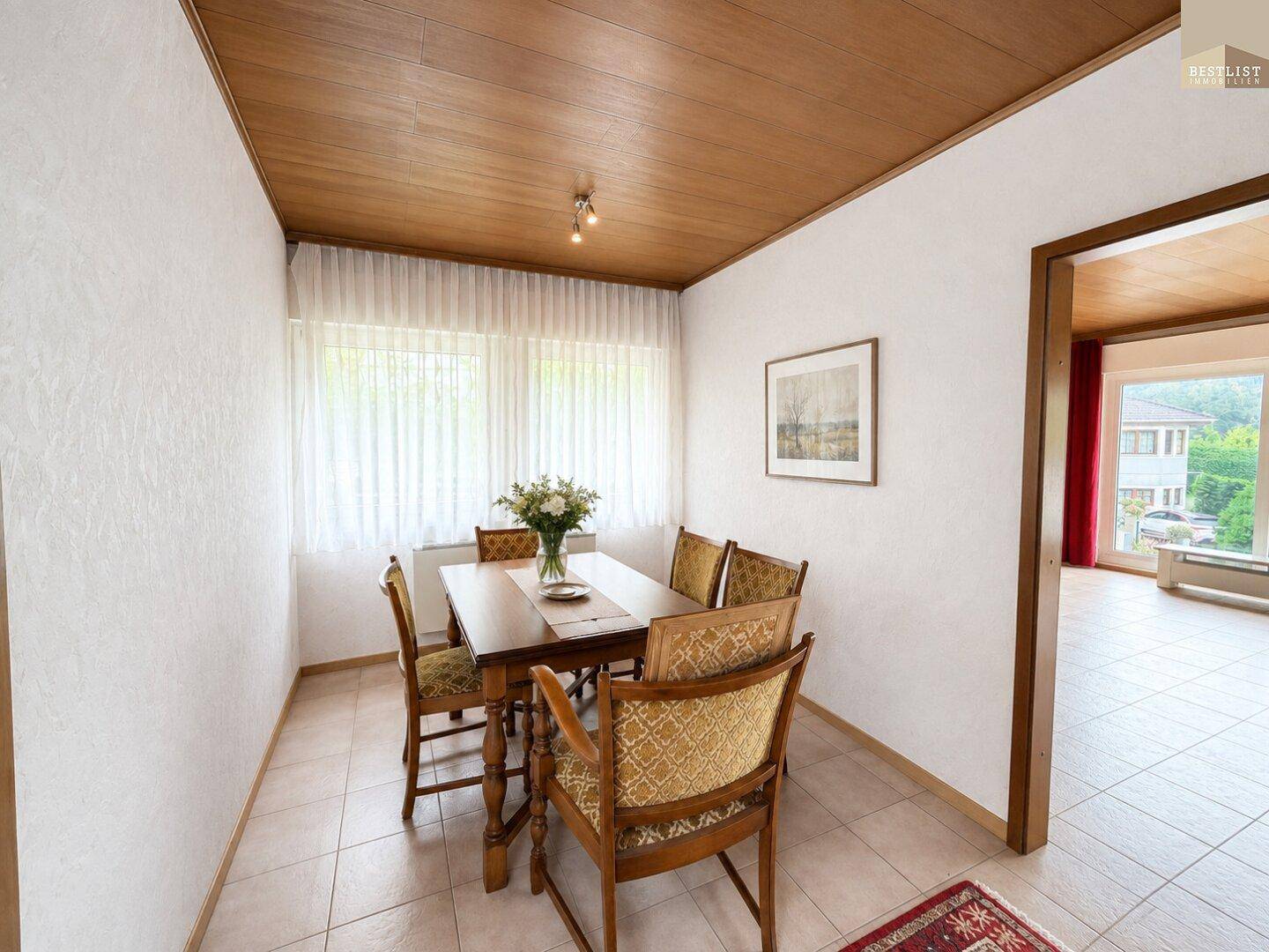 Gemütlicher Essbereich mit Holztisch und Stühlen, umgeben von hellen Wänden und einer Holzdecke.