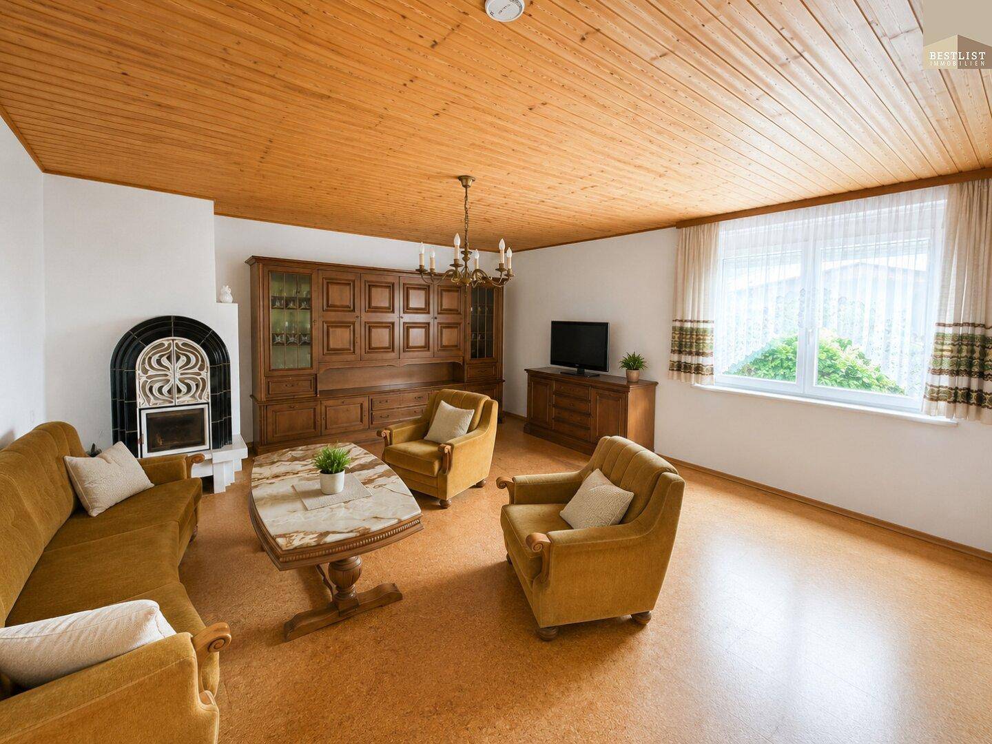 Gemütliches Wohnzimmer mit Kamin, Holzdecke und traditionellen Möbeln in warmen Farbtönen.