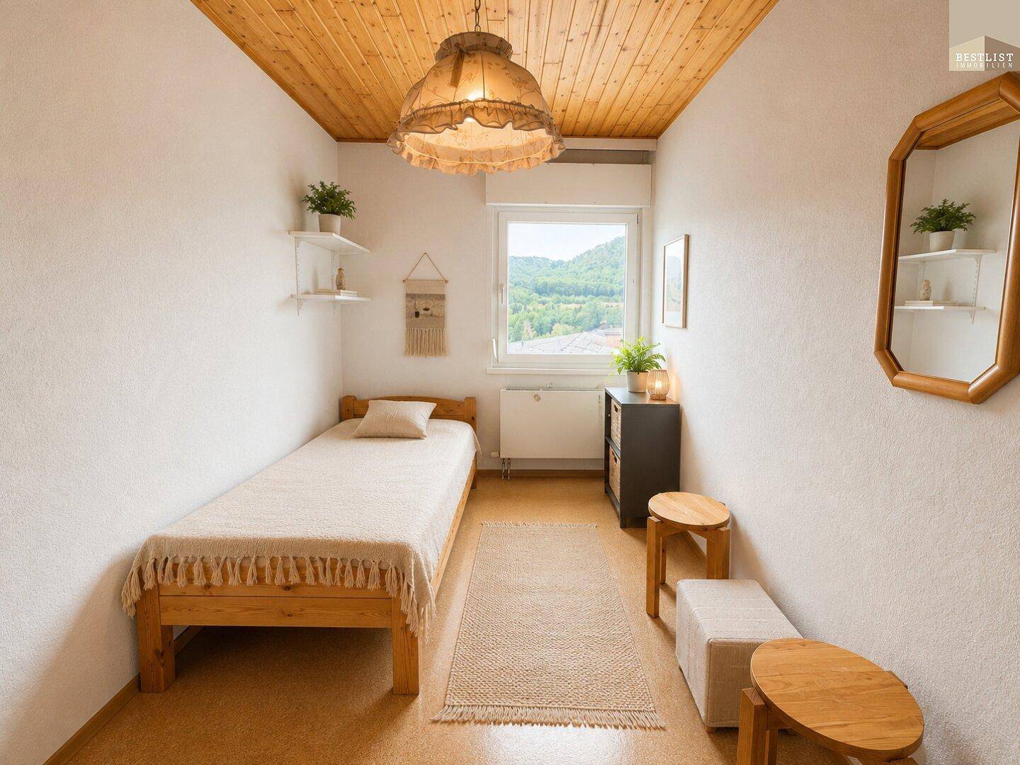Kleines Schlafzimmer mit Einzelbett, Holzdecke und Blick ins Grüne durch das Fenster.