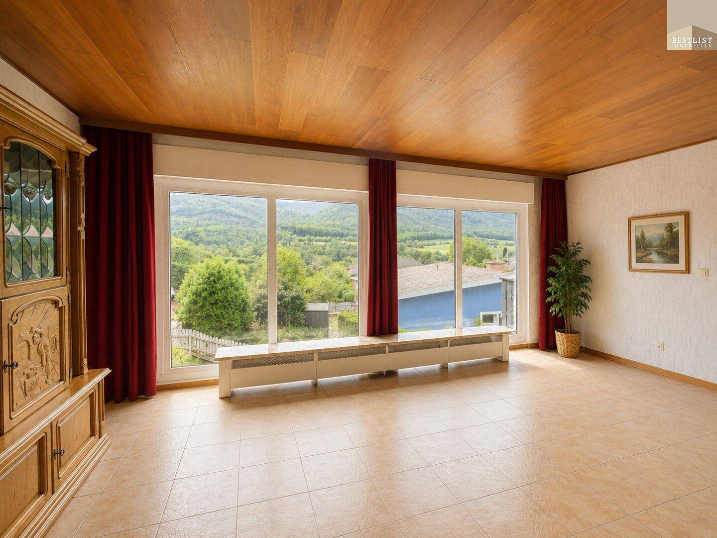 Wohnbereich mit Holzdecke und großen Fenstern, die viel Tageslicht und Landschaftsblick bieten.
