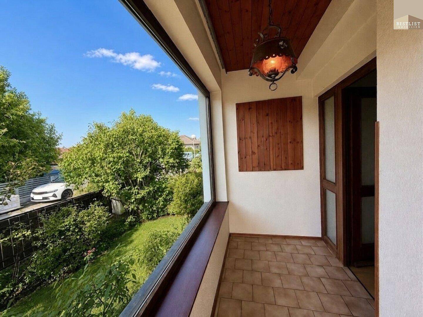 Überdachte Loggia mit Fliesenboden und Blick ins Grüne, ideal für entspannte Stunden.