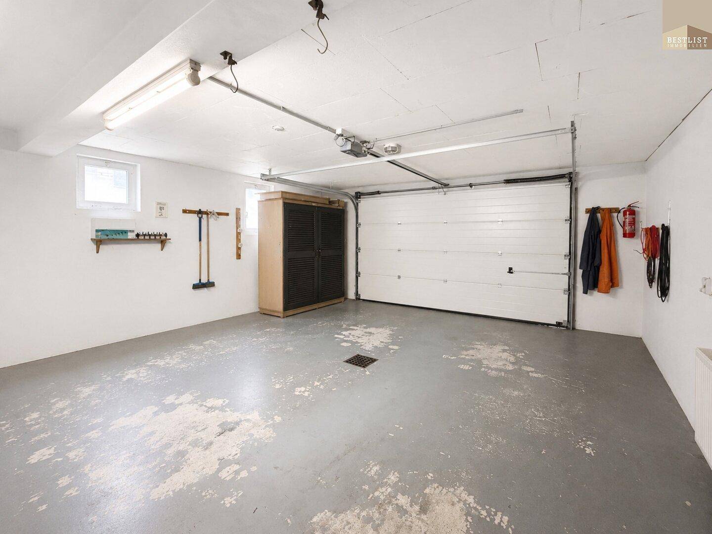 Geräumige Garage mit Rolltor, ausreichend Platz für Fahrzeuge und Lagerung.