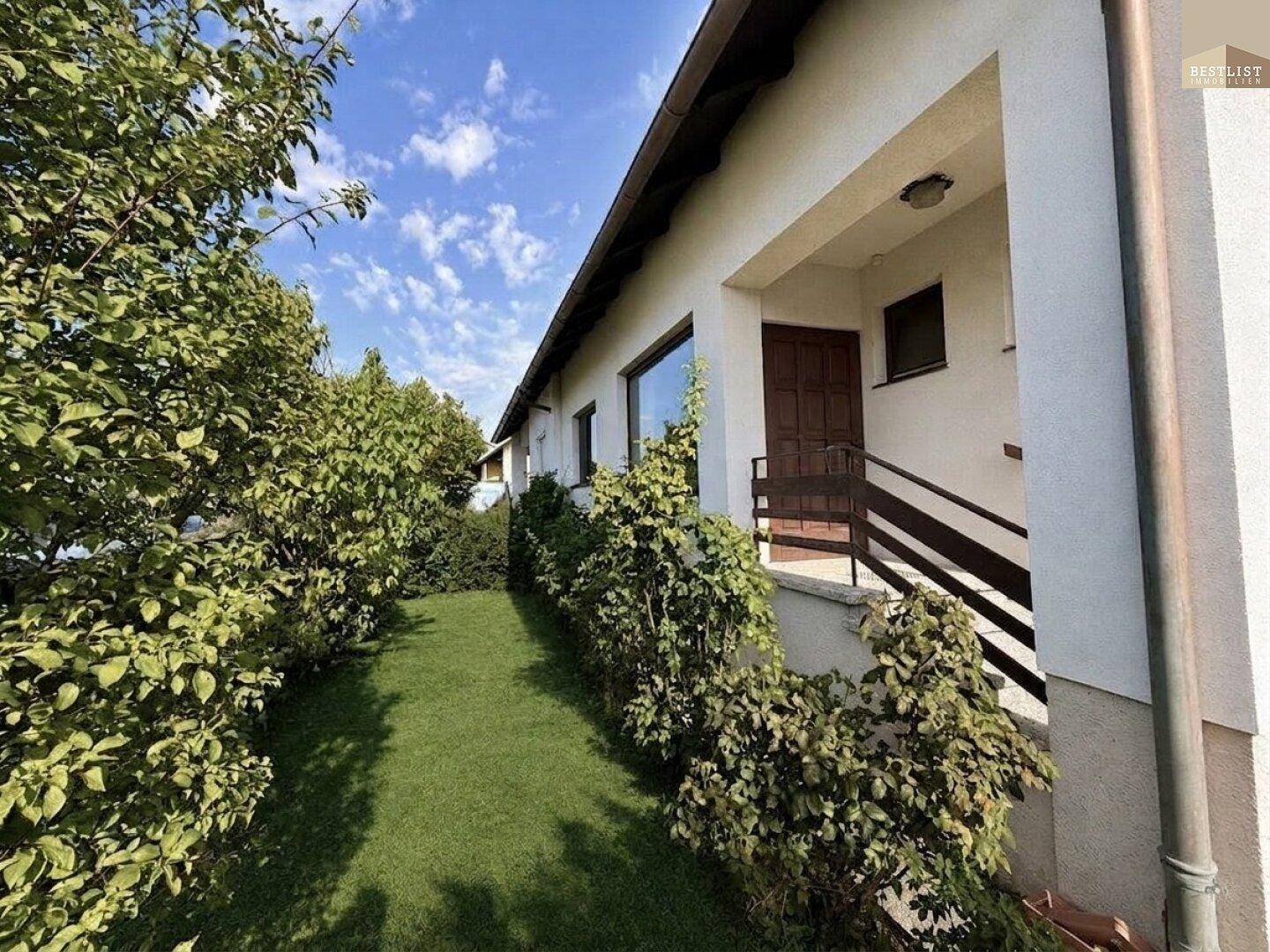 Seitlicher Eingangsbereich des Hauses mit Treppe und gepflegter Grünfläche.