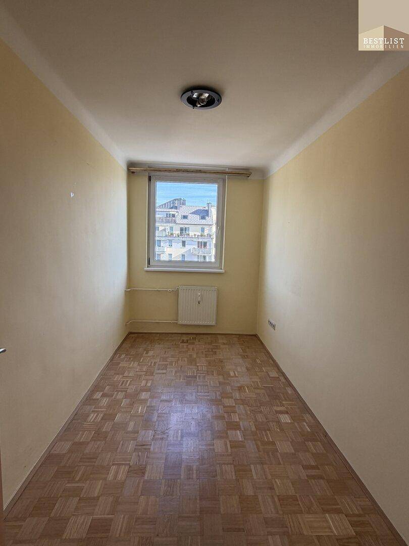 Kleines Zimmer mit Parkettboden und Fenster, ideal als Schlaf- oder Arbeitszimmer.