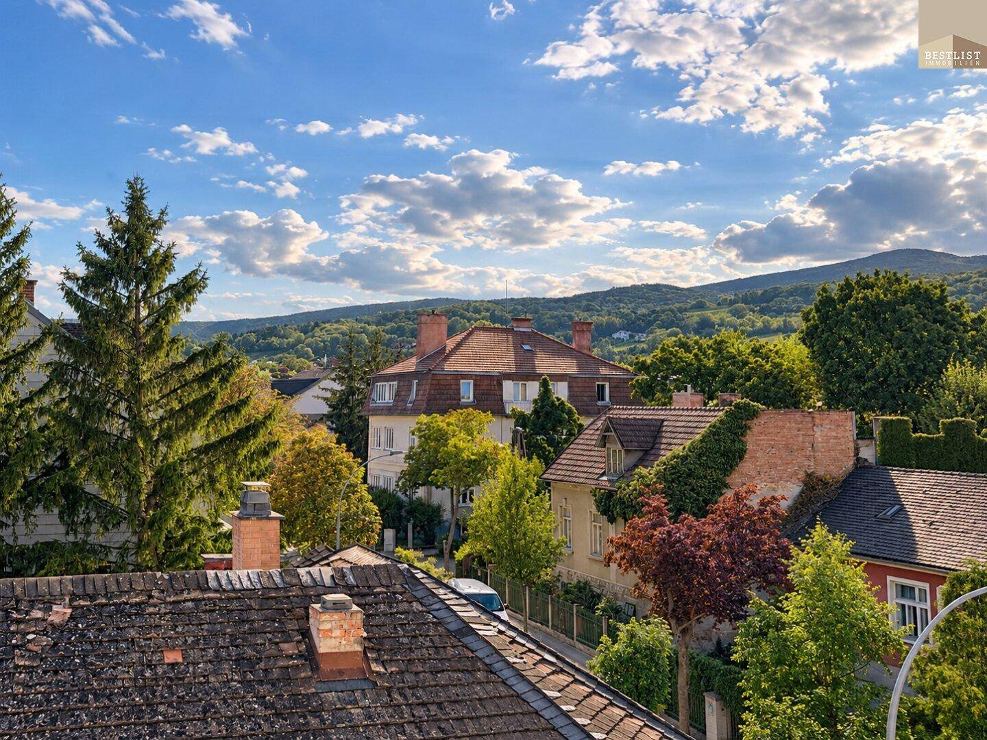 Malerische Wohngegend mit traditionellen Häusern, üppigem Grün und hügeliger Landschaft.