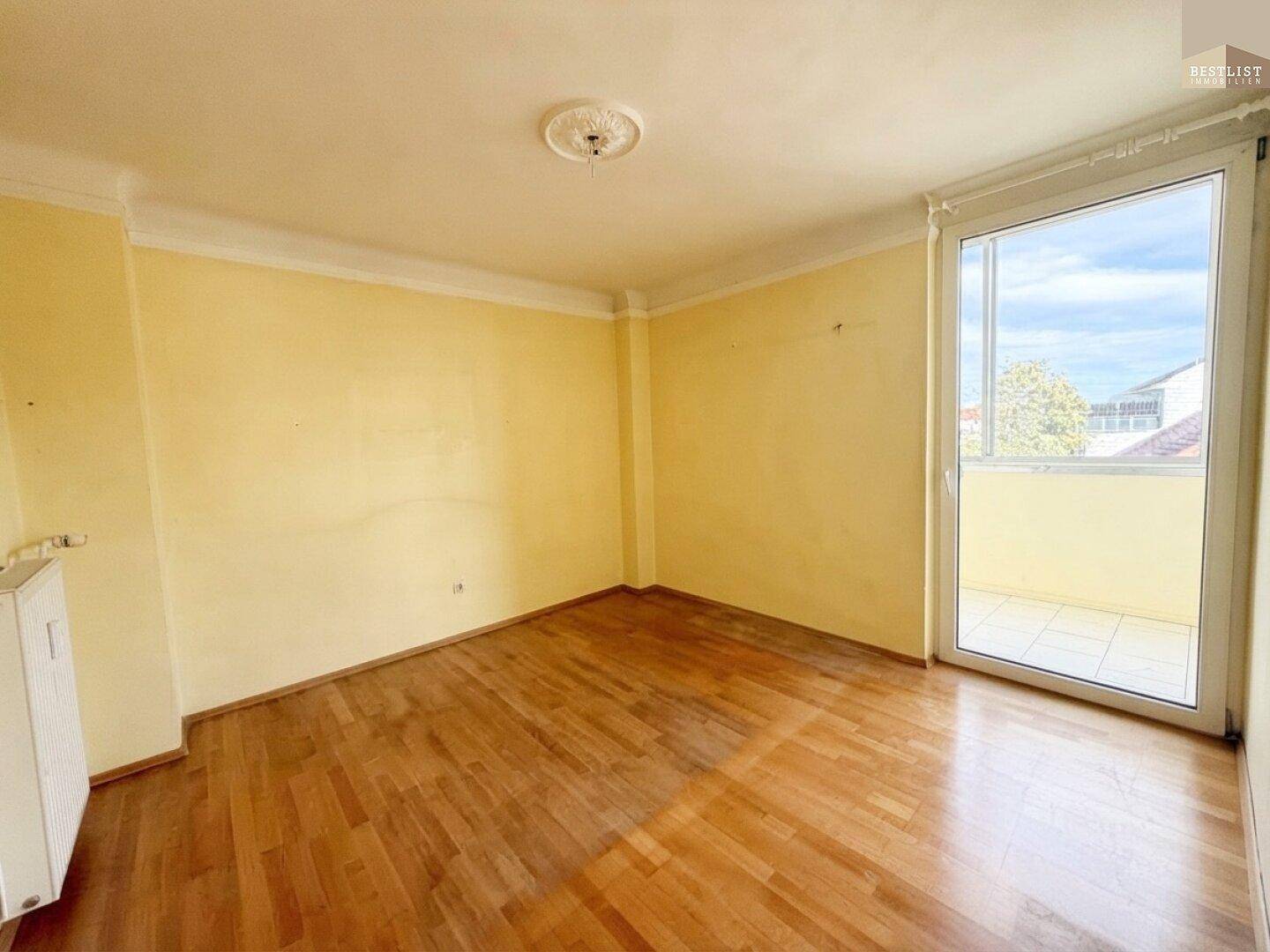 Helles Zimmer mit Holzboden und direktem Zugang zu einem sonnigen Balkon.