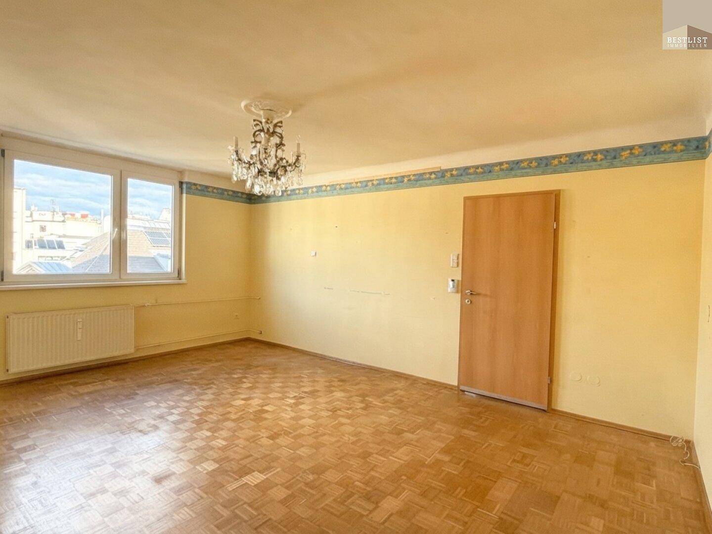 Geräumiges Wohnzimmer mit Holzboden und viel Tageslicht, ideal für individuelle Gestaltung.