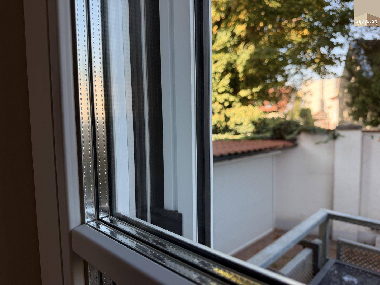 Nahaufnahme eines Fensters mit Blick auf den Außenbereich und die umliegende Bebauung.