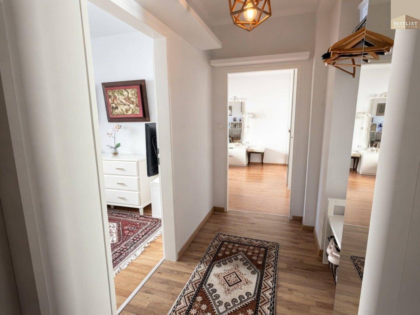Heller Flur mit Holzboden und Spiegeln, der die verschiedenen Räume der Wohnung verbindet.