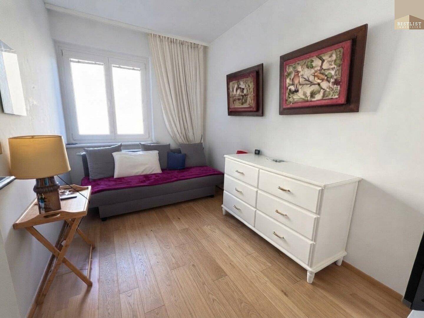 Gemütliches Schlafzimmer mit Holzboden, Sofa und Kommode, ideal als Gästezimmer oder Büro.