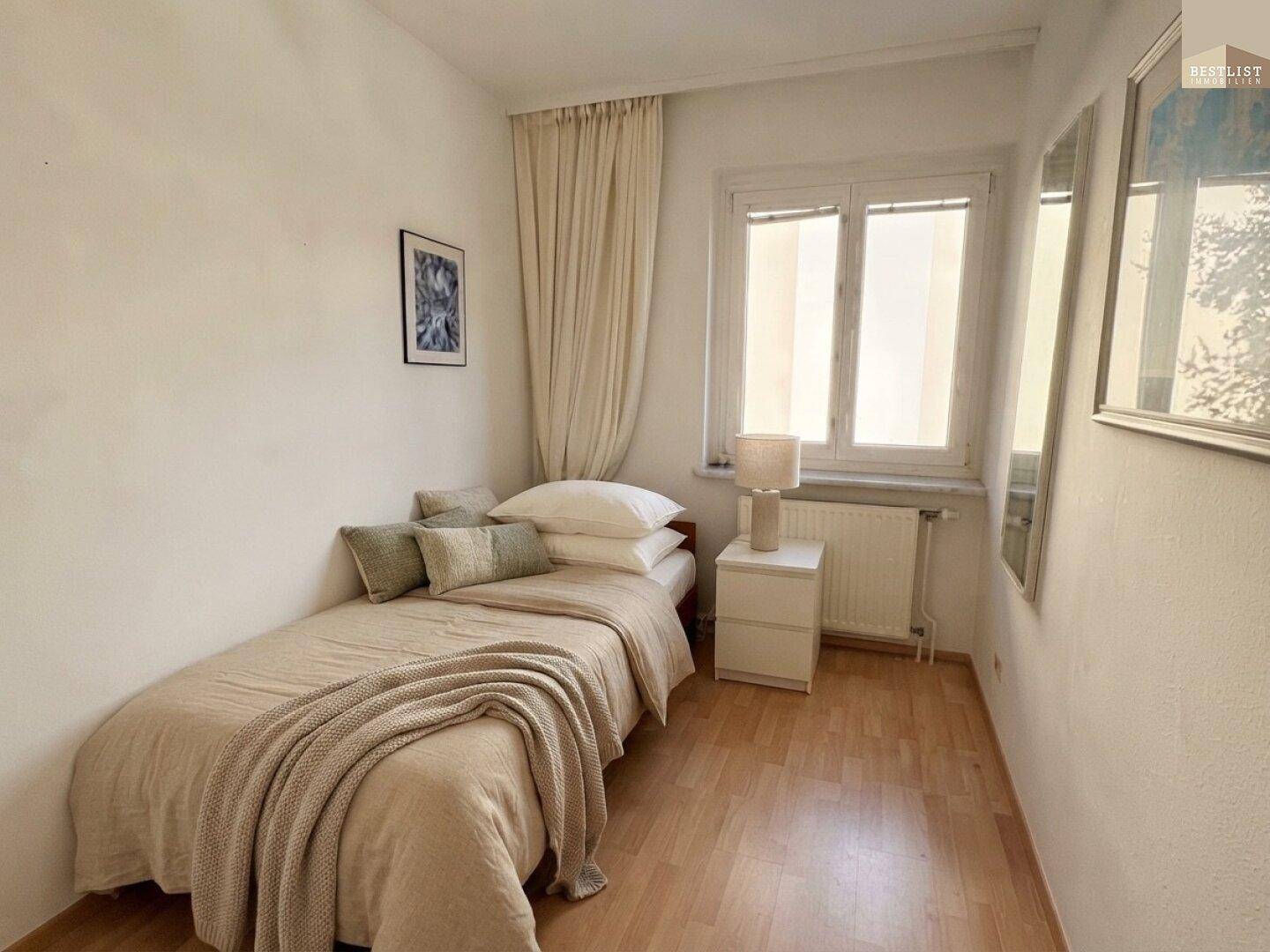 Kleines Schlafzimmer mit Einzelbett, Holzboden und Fenster, das für ausreichend Tageslicht sorgt.