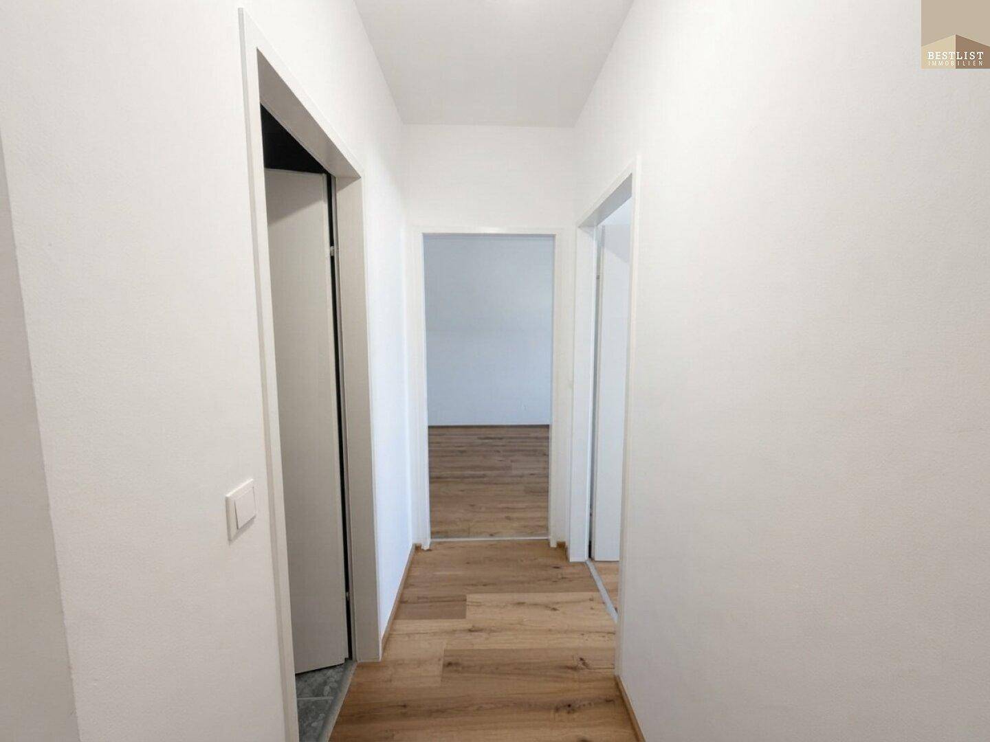 Heller Flur mit Holzboden, der zu den verschiedenen Zimmern der Wohnung führt.