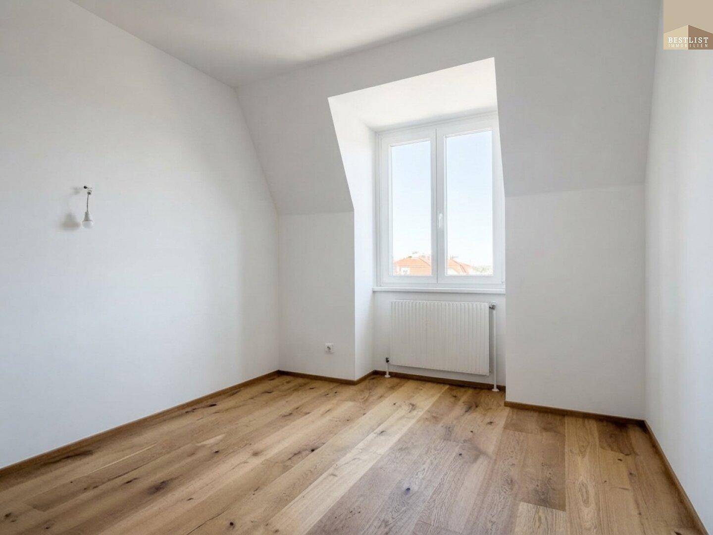 Helles Zimmer mit Holzboden und Dachschrägen, bietet eine gemütliche Atmosphäre.