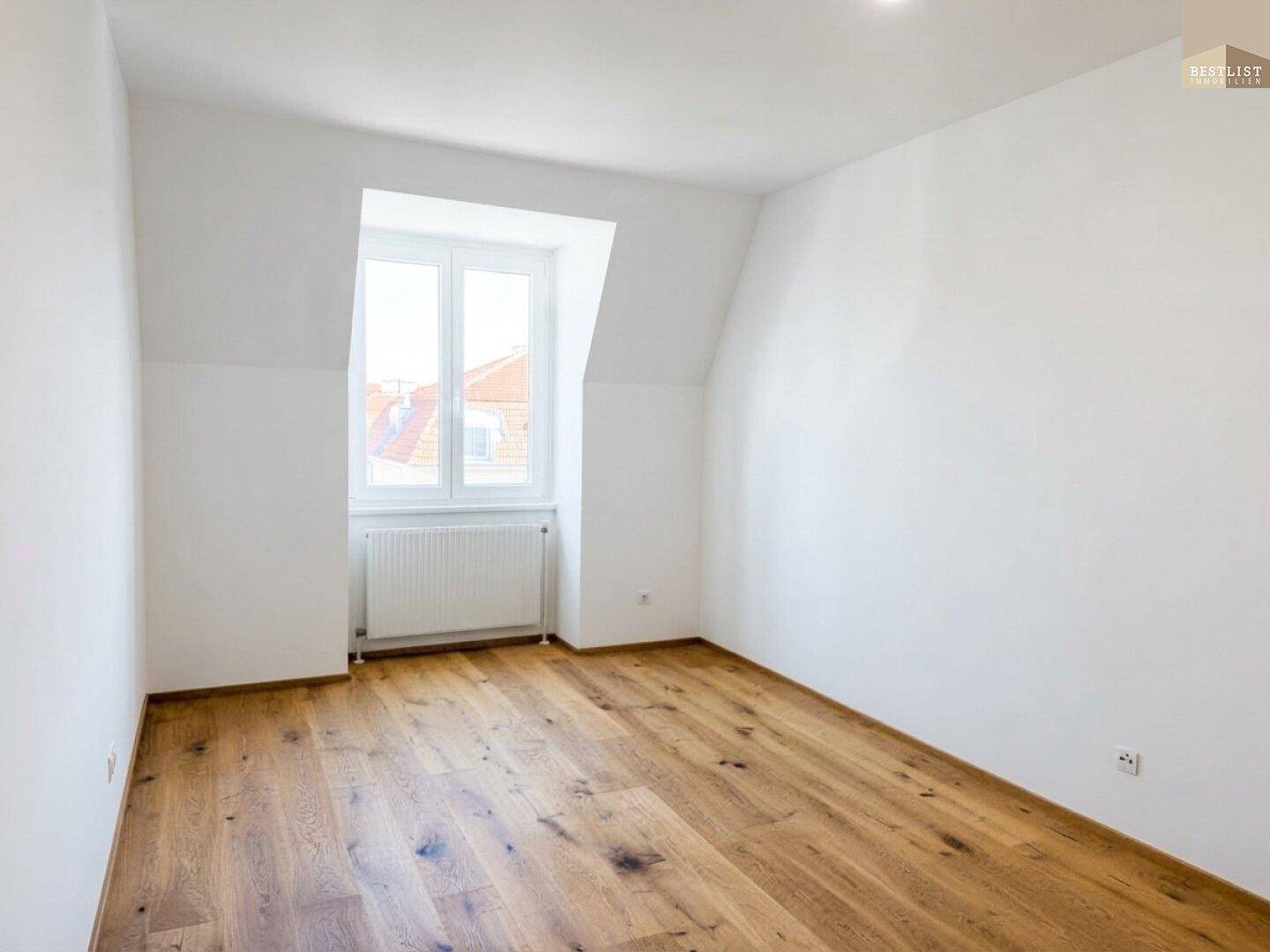 Geräumiges Zimmer mit Holzboden und viel Tageslicht, ideal als Schlafzimmer nutzbar.