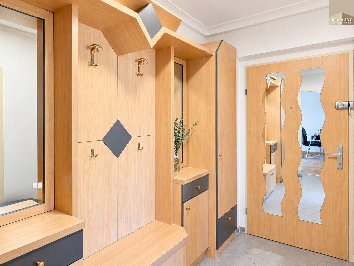 Heller Eingangsbereich mit Holzgarderobe, Spiegeln und einem pflegeleichten Fliesenboden.