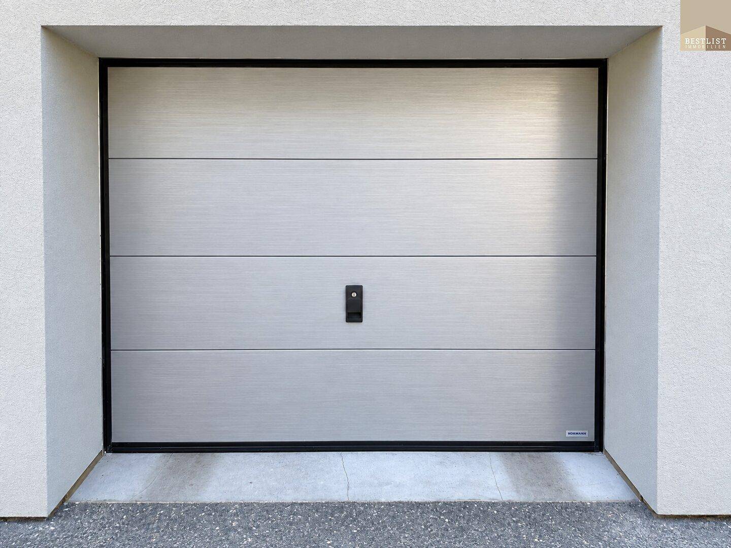 Moderne Garagentür aus Metall, harmonisch in die Fassade des Gebäudes integriert.