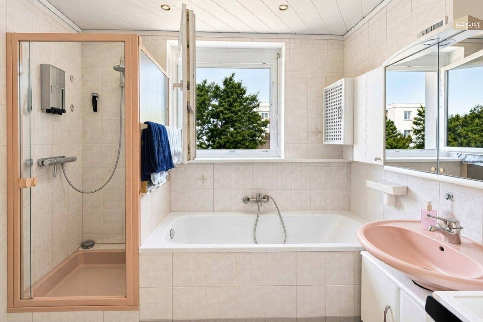 Helles Badezimmer mit Badewanne, separater Dusche und einem Fenster für Tageslicht.