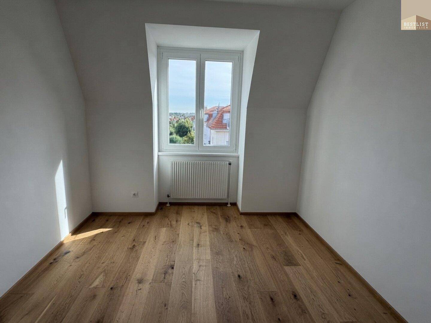 Lichtdurchflutetes Zimmer mit Holzboden und Ausblick, bietet eine angenehme Wohnatmosphäre.