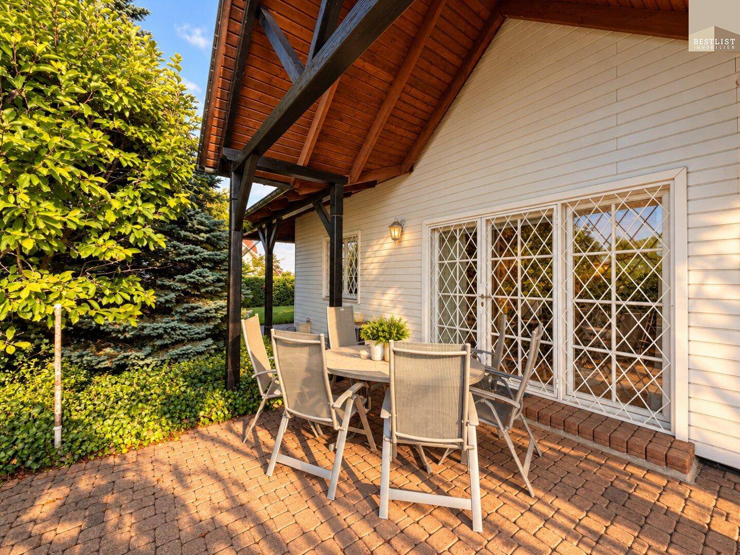 Gemütliche gepflasterte Terrasse mit Gartenmöbeln und Zugang zum Haus, ideal für Mahlzeiten im Freien.