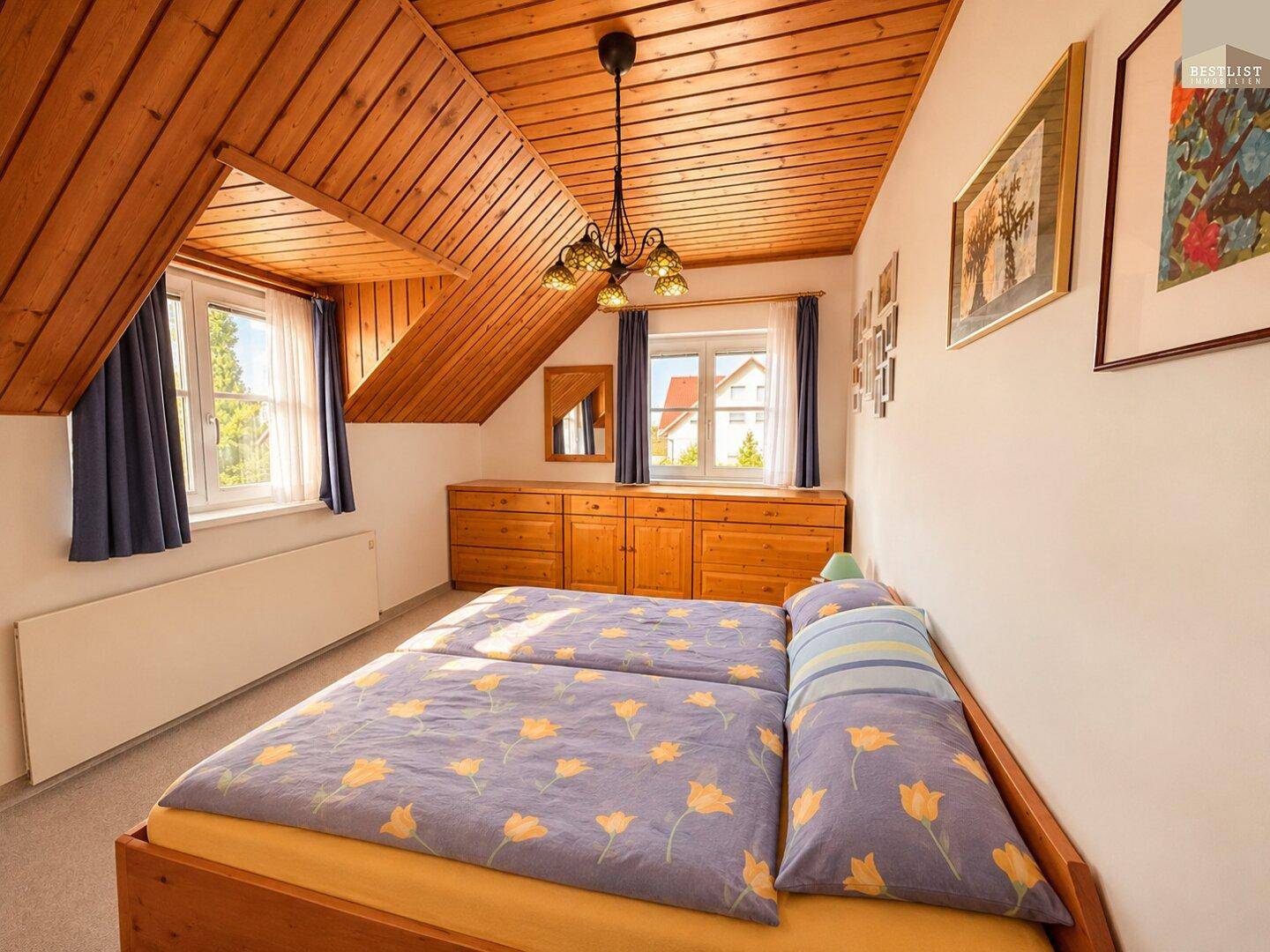 Schlafzimmer mit Holzdecke, Dachschräge und zwei Einzelbetten, die eine gemütliche Atmosphäre schaffen.