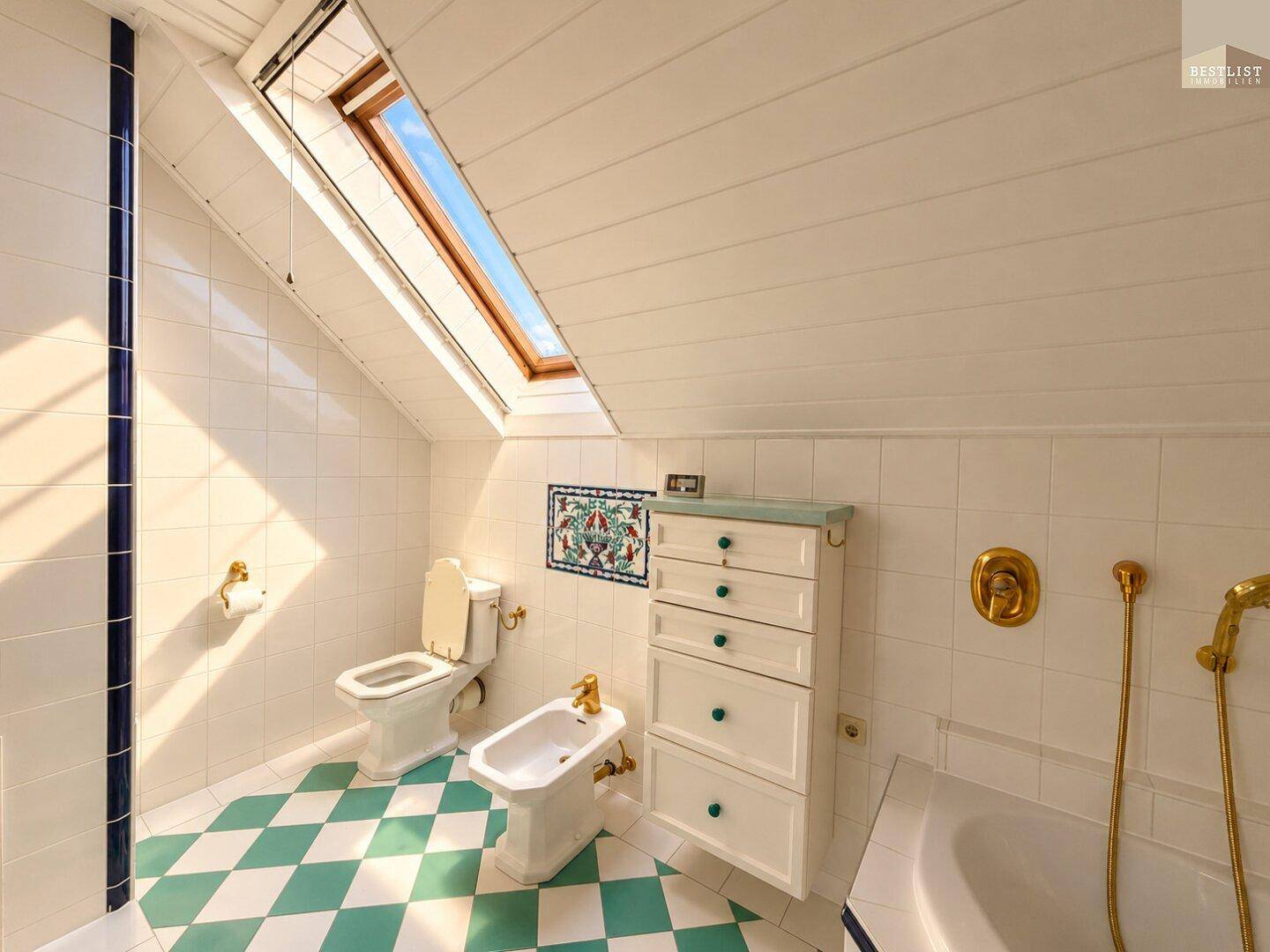 Badezimmer mit Dachschräge, Oberlicht, WC, Bidet und auffälligen Fliesen im Retro-Stil.