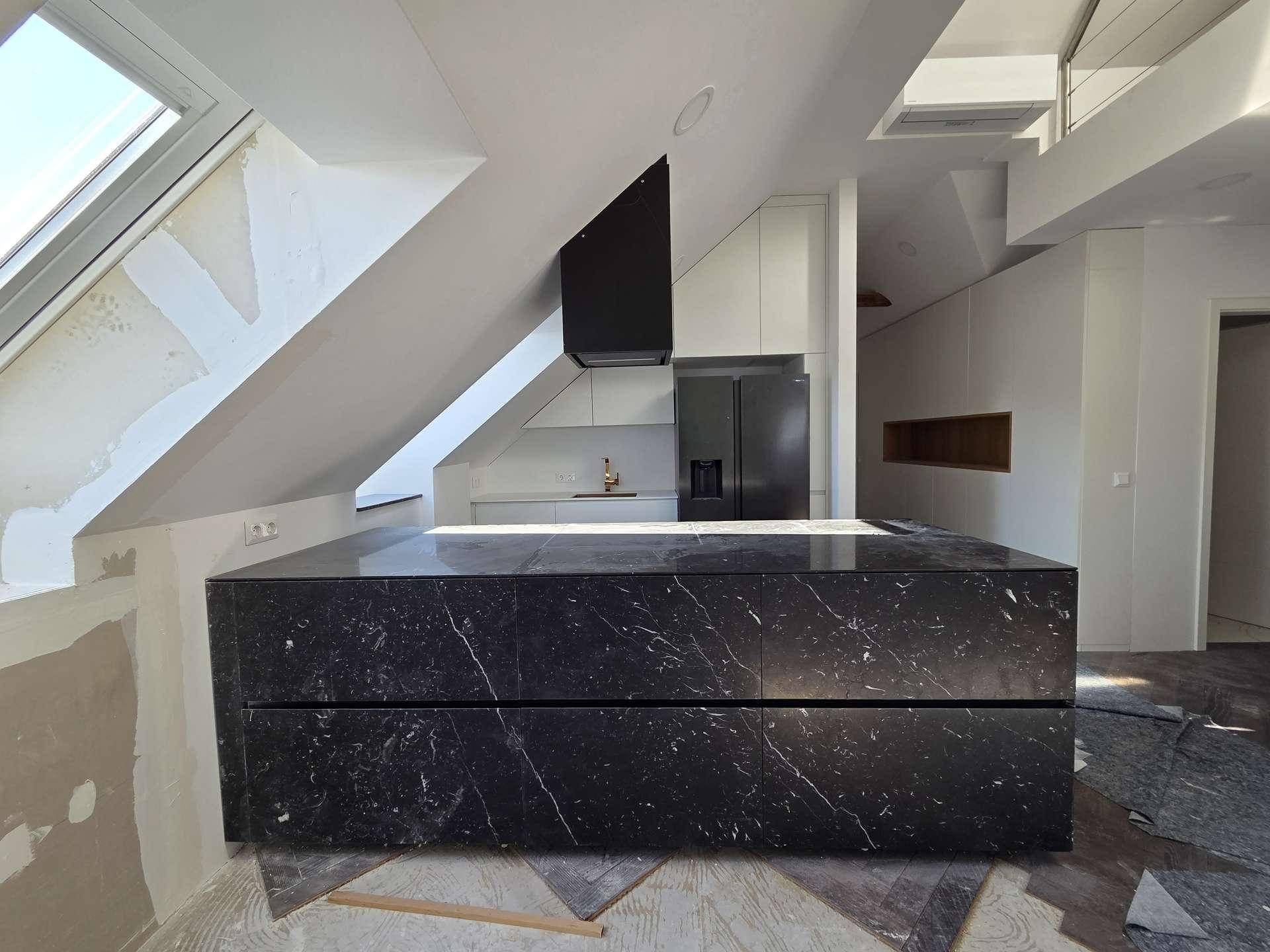 Moderne Kücheninsel aus schwarzem Marmor in einem hellen Raum mit Dachschräge und Oberlicht.