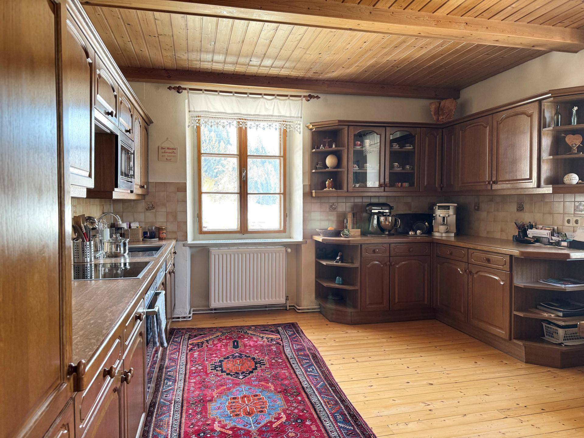 Traditionelle Holzküche mit vielen Schränken, Holzboden und einem Fenster.