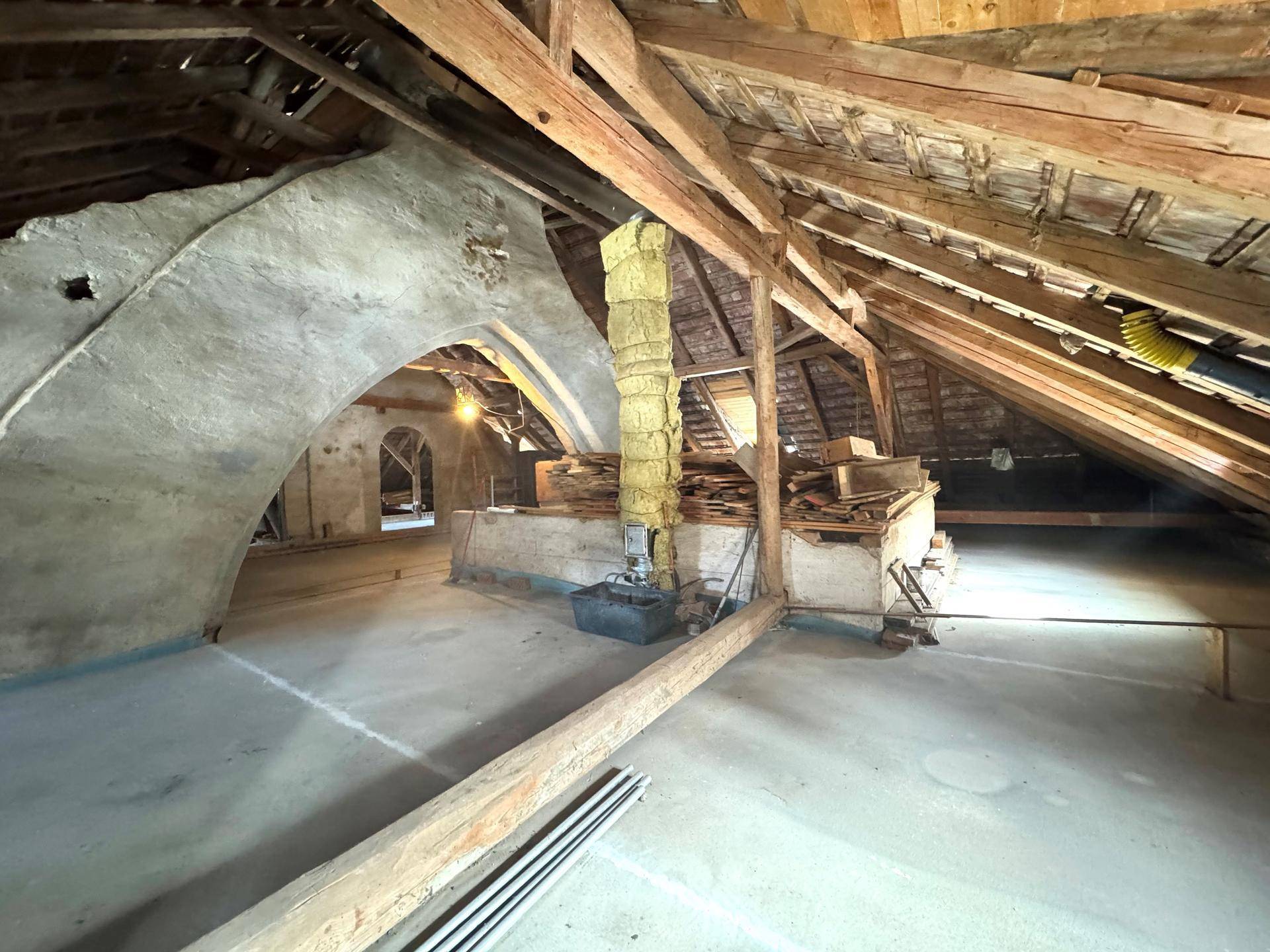 Geräumiger Dachboden mit freiliegenden Holzbalken und Betonboden, bereit zum Ausbau.
