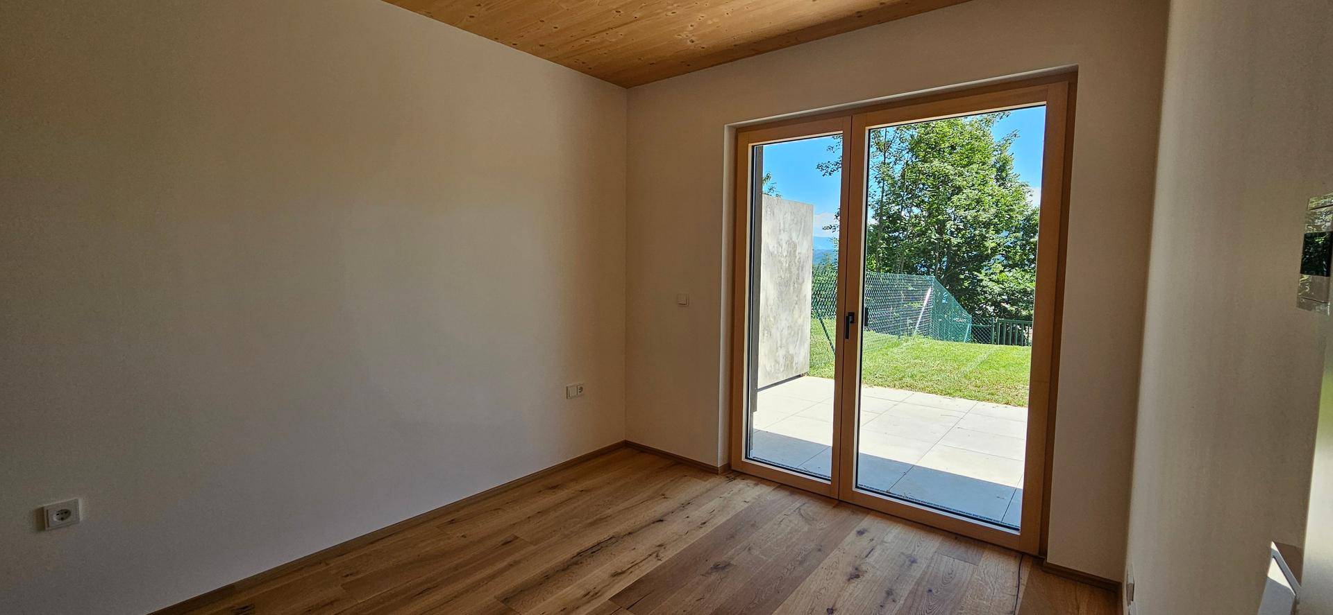 Helles Schlafzimmer mit Holzboden und Zugang zu einer Terrasse oder dem Garten.