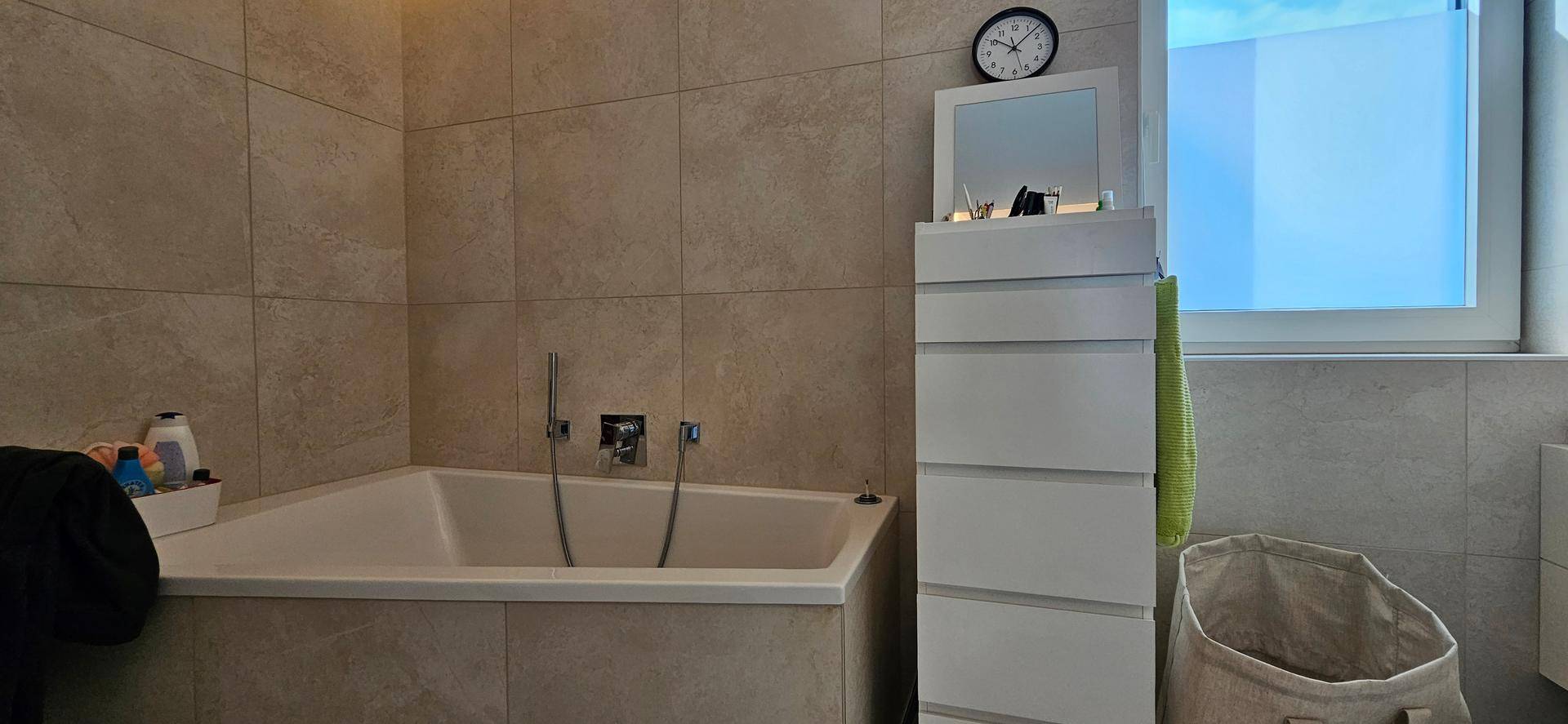 Modernes Badezimmer mit eingebauter Badewanne, beigefarbenen Fliesen und Fenster.