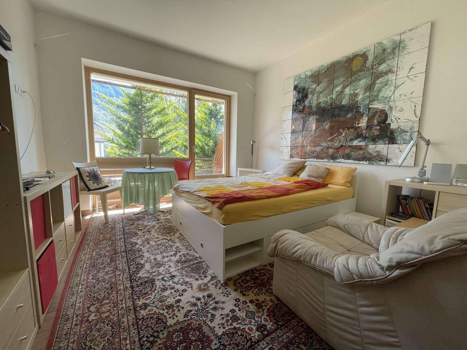 Helles Schlafzimmer mit großem Fenster, das einen schönen Blick auf die Berge und Bäume bietet.