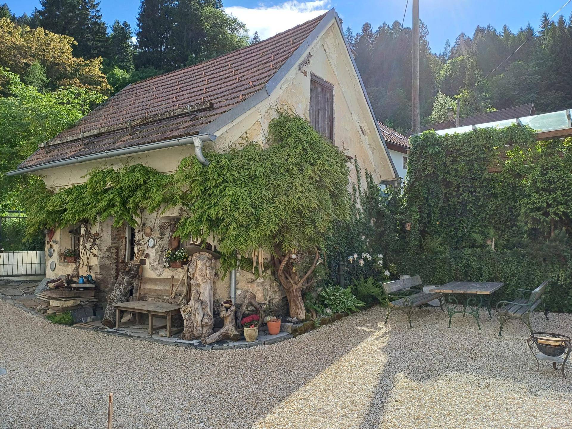 Charmantes Nebengebäude umgeben von üppigem Grün und alten Bäumen.