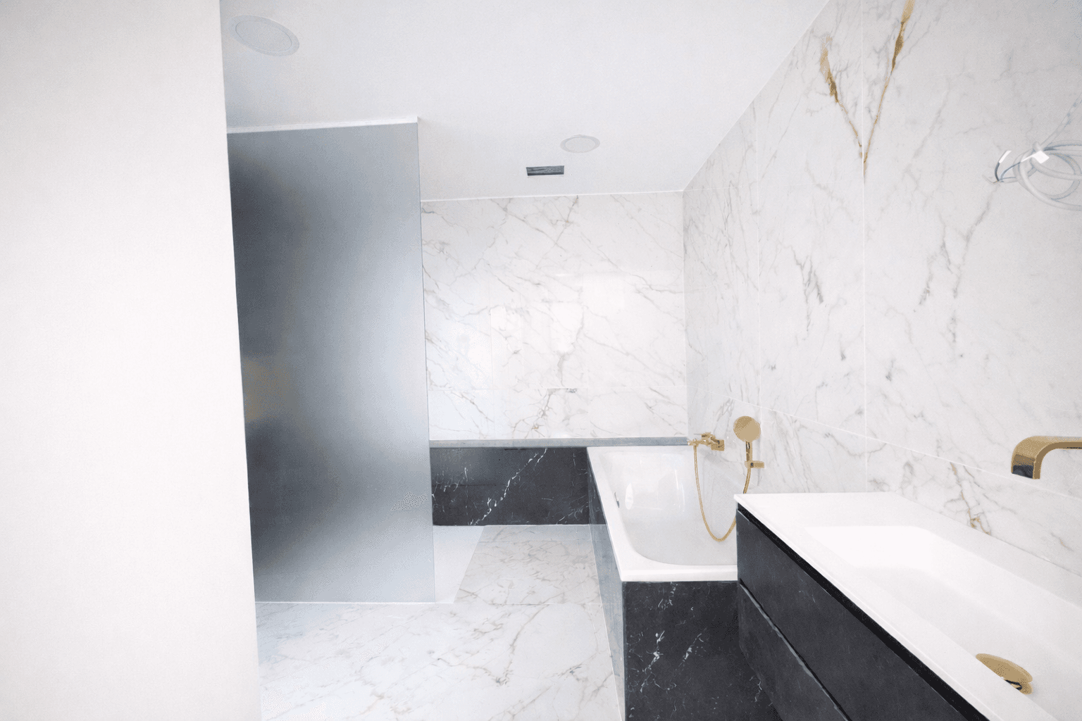 Elegantes Badezimmer mit Badewanne, Waschtisch und luxuriösen Marmorfliesen in Schwarz-Weiß.