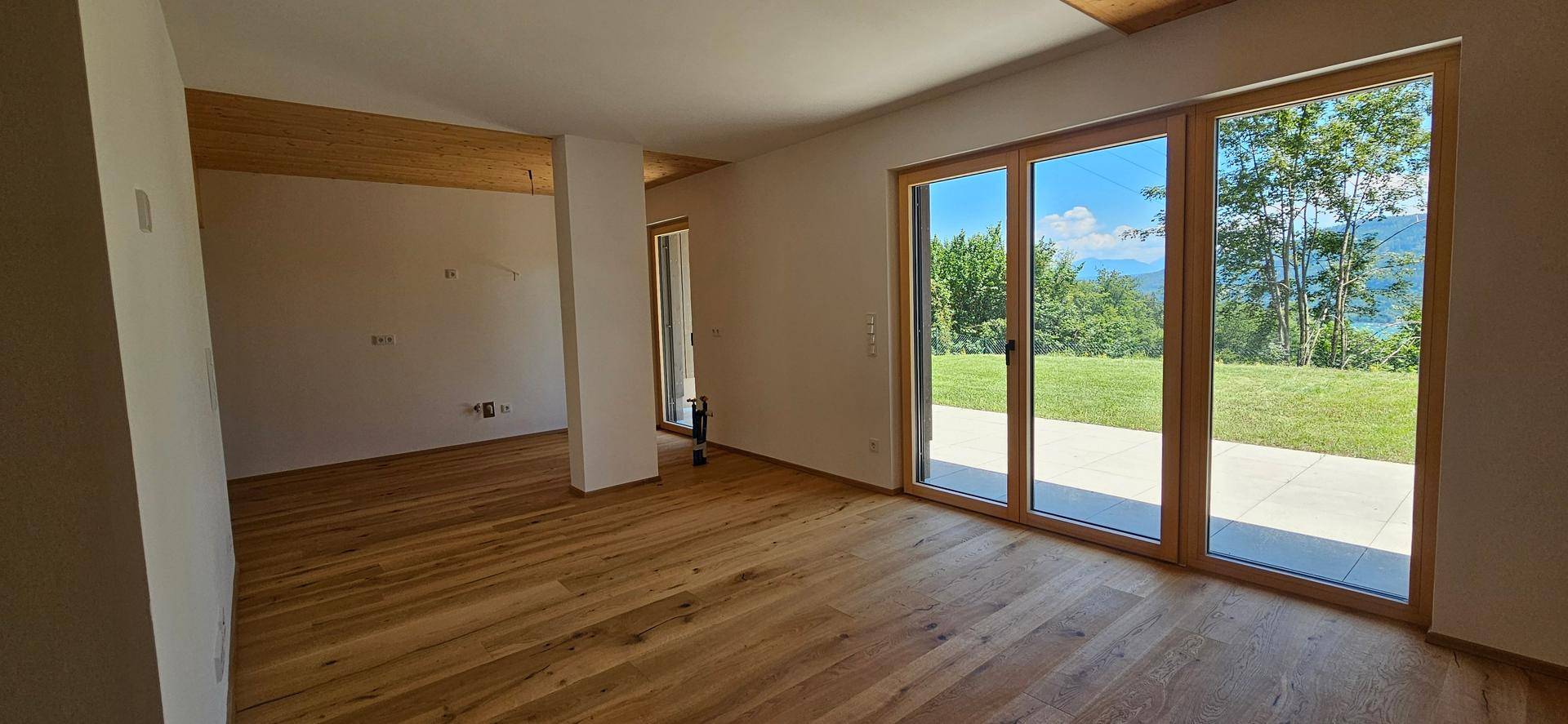 Geräumiger, lichtdurchfluteter Wohnbereich mit Eichenparkett und Zugang zur Terrasse mit Seeblick.