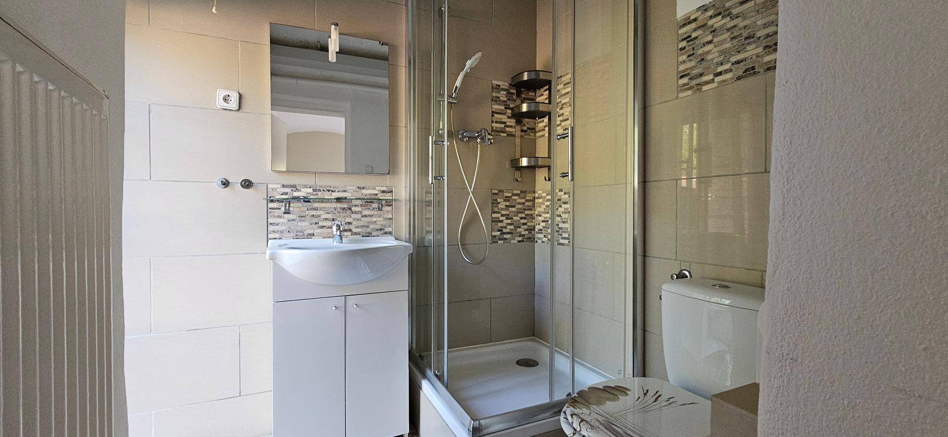 Modernes Badezimmer mit Duschkabine, Waschbecken und Wandspiegel.