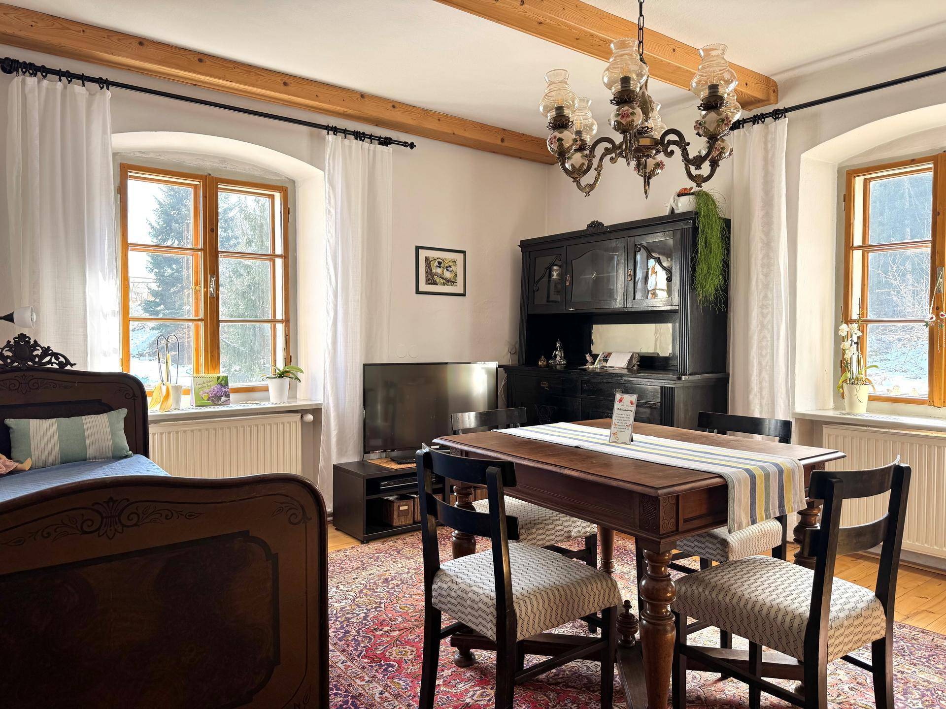 Schlafzimmer mit Holzbalkendecke, traditionellem Bett und kleinem Essbereich.