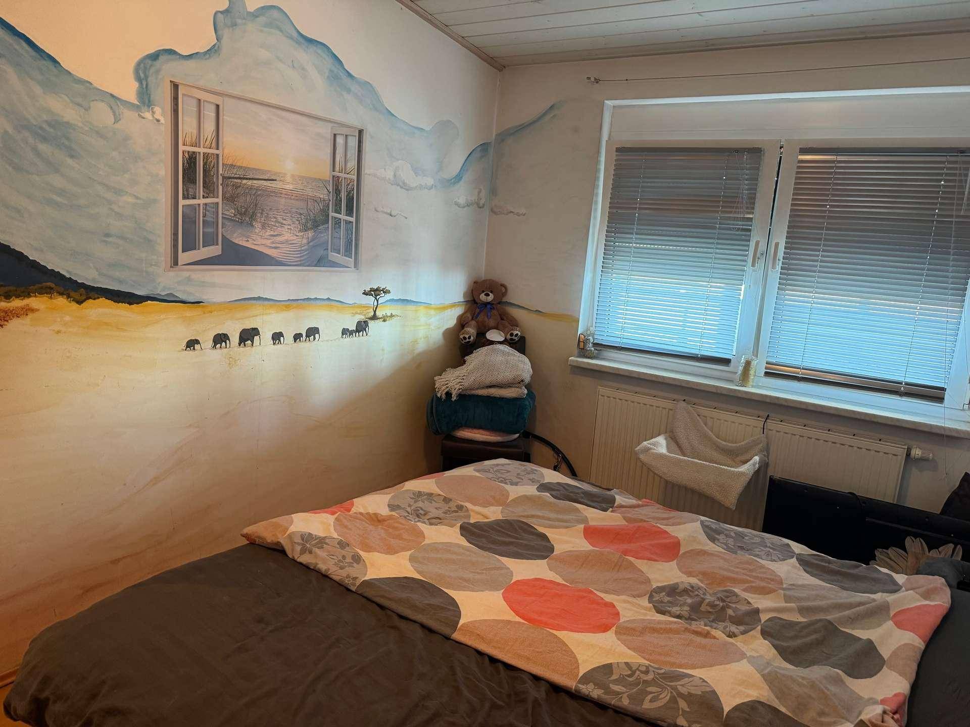 Schlafzimmer mit gemütlichem Bett, Fenster mit Jalousien und einer kreativen Wandmalerei.