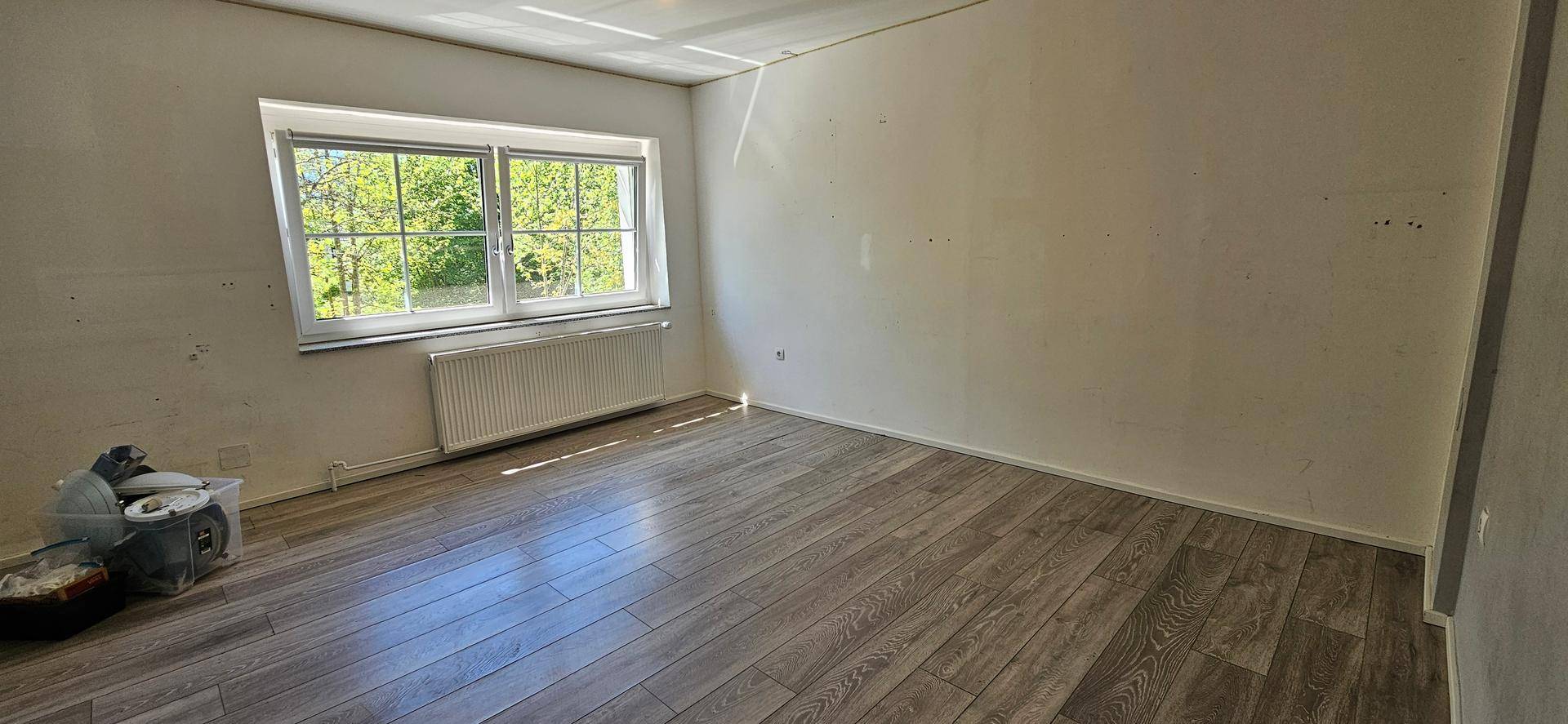 Geräumiges Schlafzimmer mit Holzboden, Fenster und viel Tageslicht.