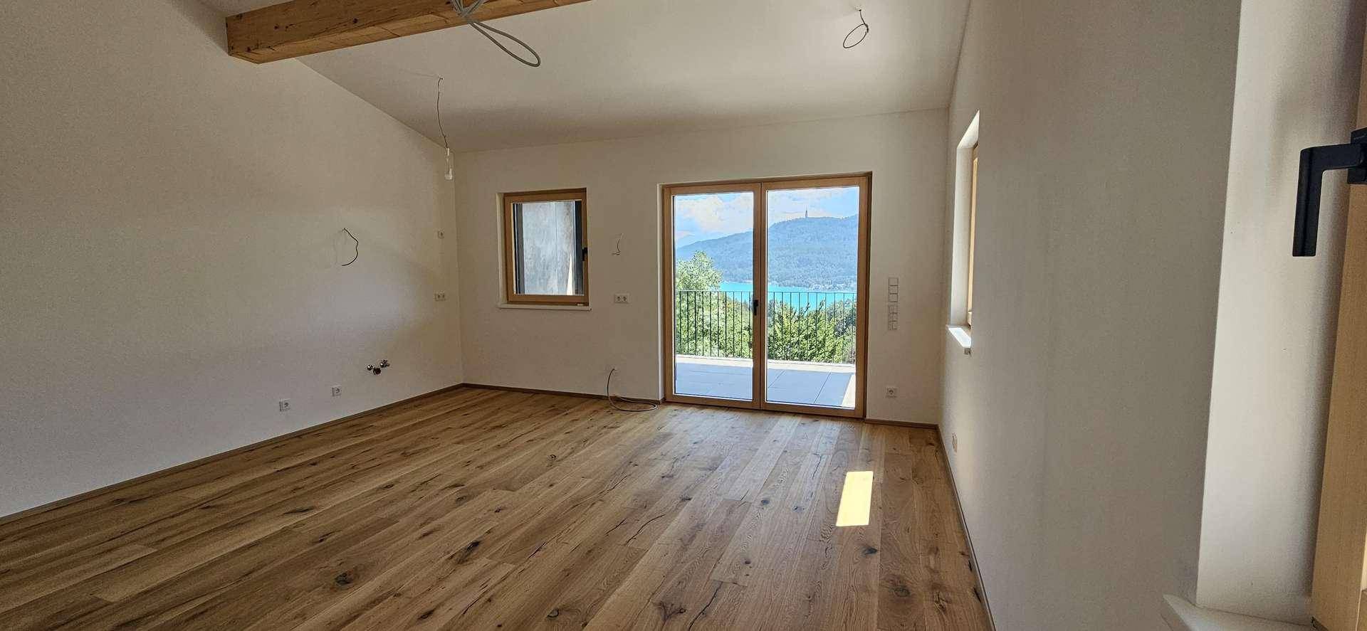 Heller Wohnraum mit Holzboden und großen Fenstern, die einen weiten Seeblick bieten.